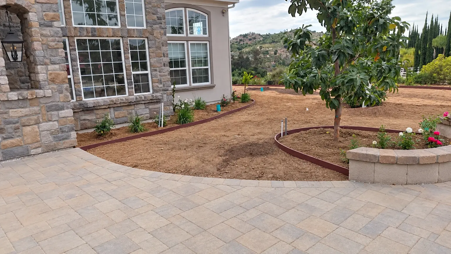 Before: Prepared soil and curved planting beds beside the courtyard. Photo retouched to remove temporary equipment and clutter.