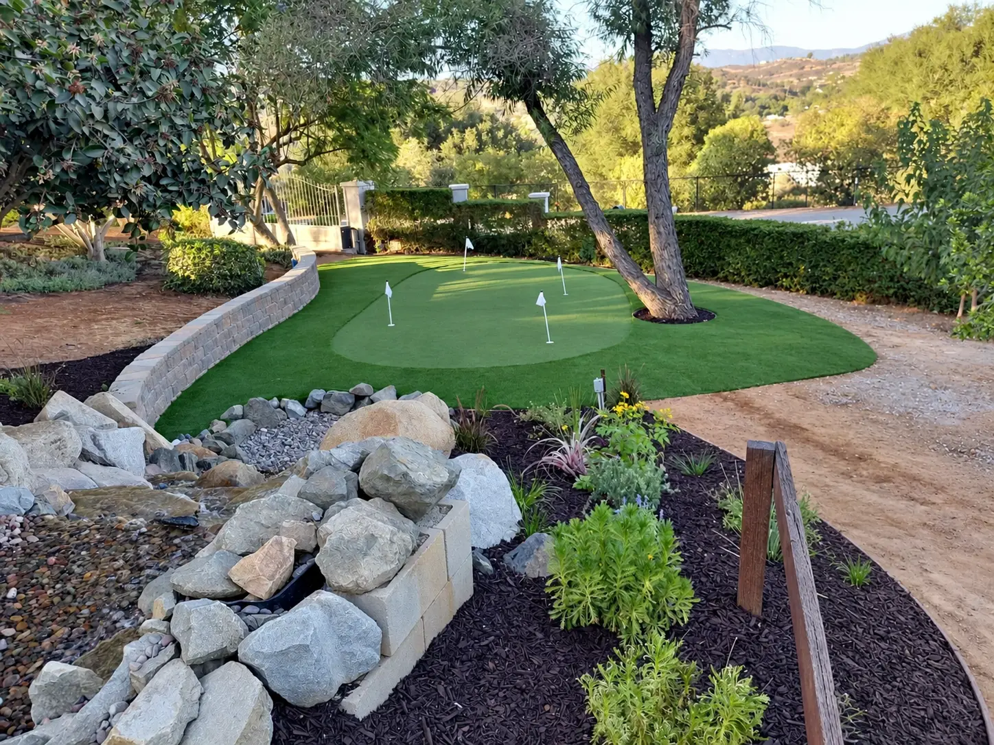 The putting green, planting beds, and stone water feature. Photo retouched to remove temporary equipment and clutter.