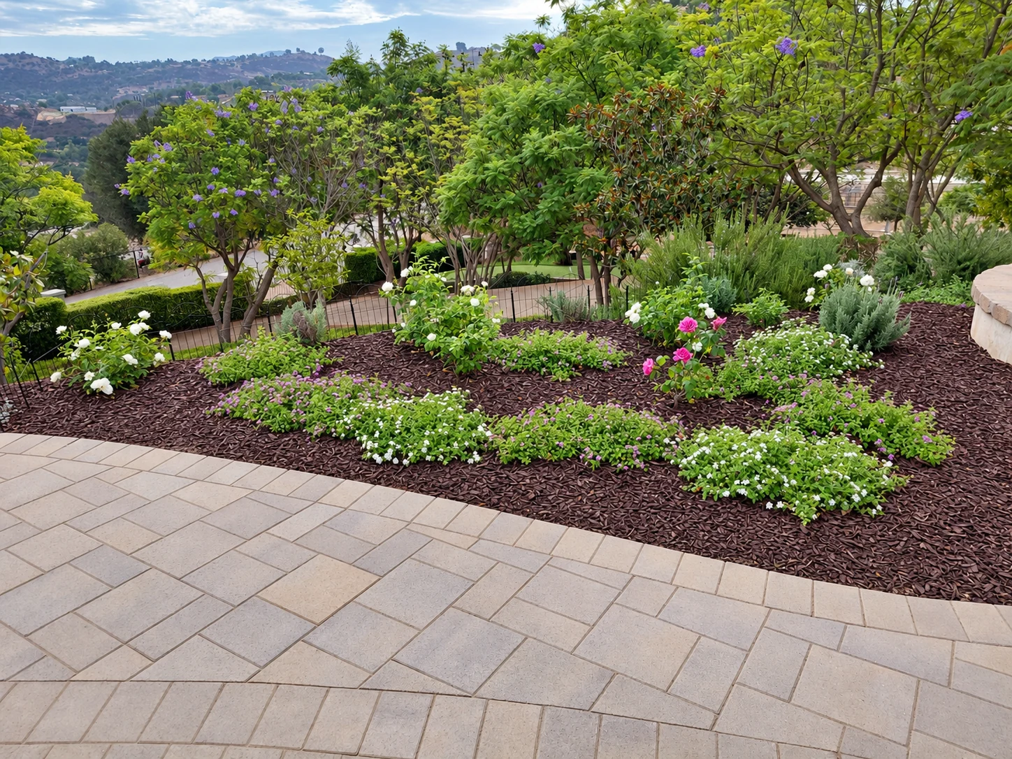 Flowering plants and mulch beside a paver patio. Photo lightly retouched.