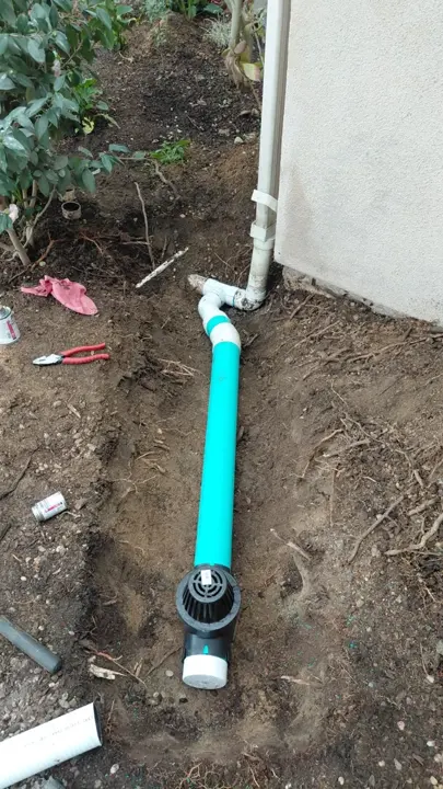 A downspout connection and drain fitting exposed for work.
