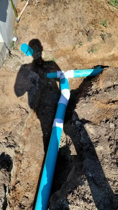 A pipe junction exposed in a landscape trench.