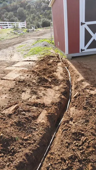 A narrow trench following the edge of an outbuilding.