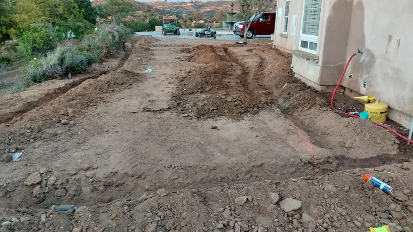 Ground preparation along the house before lawn installation.