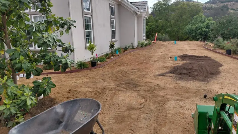 Final soil preparation between the house and planting beds.