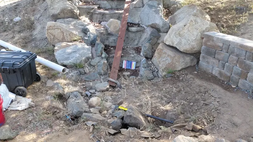 Rock water-feature construction beside the landscape wall.
