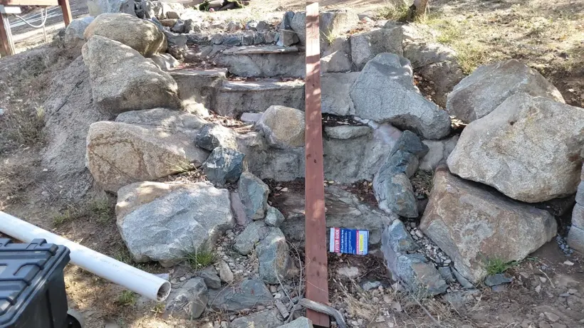 Stacked boulders taking shape around a rock water feature.