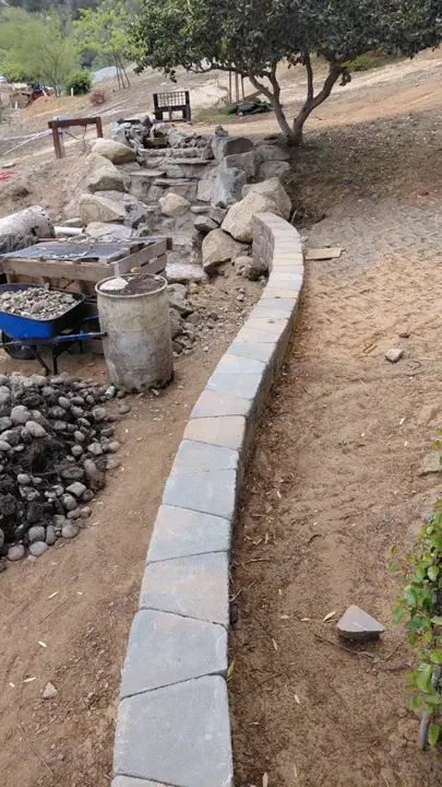 A curved block border beside the boulder water feature.
