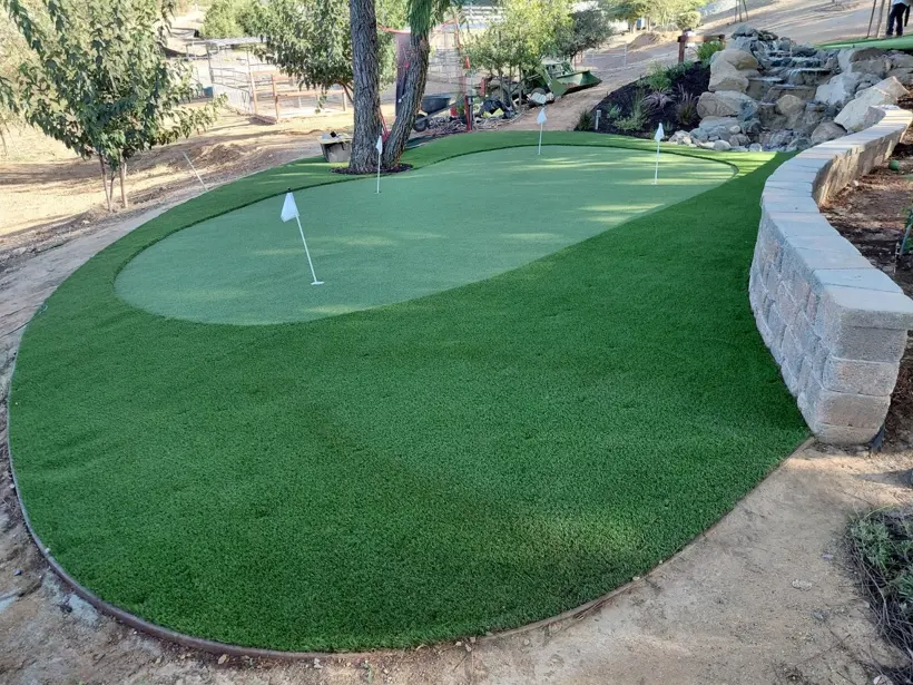 A curved putting green beside a low block landscape wall.