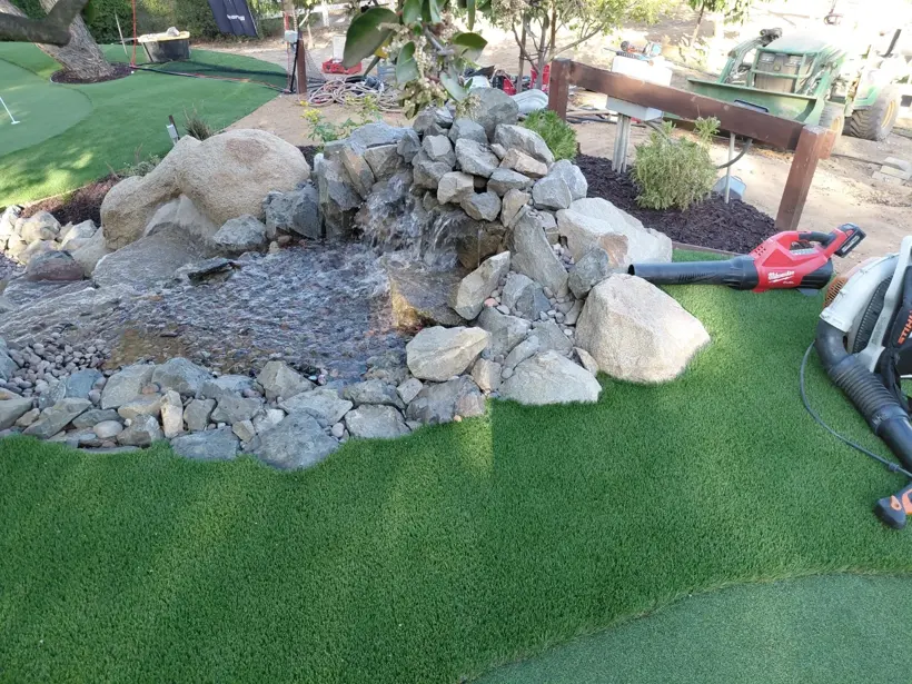 A boulder feature with river rock beside the putting green.