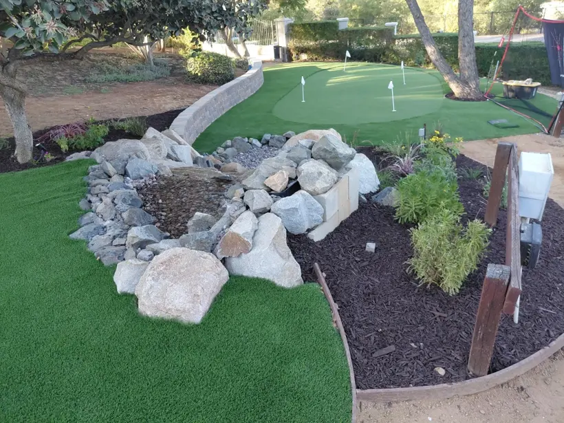 Putting green, boulders, and mulched planting viewed together.