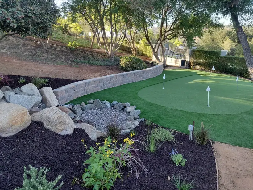 Putting green, rock feature, and freshly mulched planting beds.