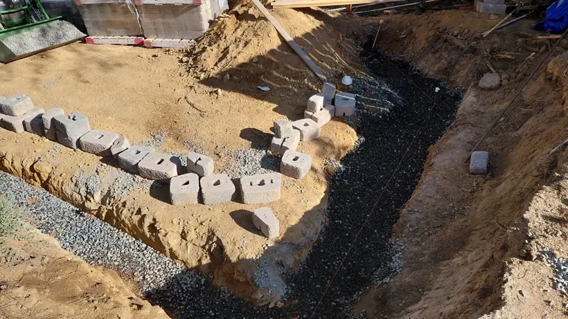 A curved block-wall footing on a prepared gravel base.