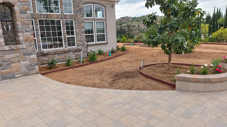 Prepared soil and curved planting beds beside the courtyard. Photo retouched to remove temporary equipment and clutter.